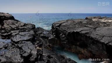 海水从夏威夷火山岩石形成的天然拱门下飞溅出来，皮划艇划行而过